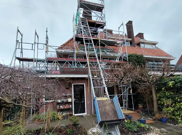 Steiger en materiaallift — Werkvoorzieningen bij een woning tijdens werkzaamheden aan het pannendak.
