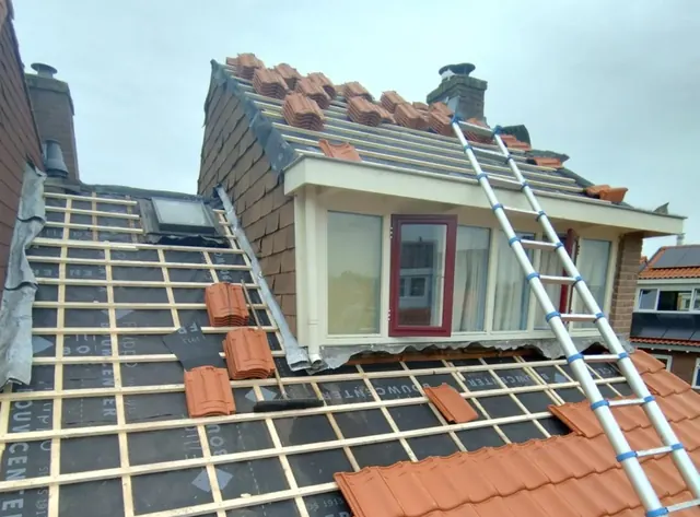 Rode pannen en panlatten — De opbouw van een pannendak rond een dakkapel is tijdens het werk zichtbaar.